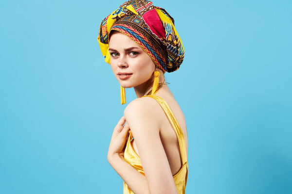 Pretty woman in multicolored turban attractive look Jewelry smile blue background. High quality photo