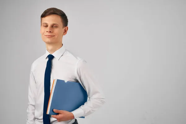 Mann im Hemd mit Krawatte blauer Ordner in den Händen grauer Hintergrund — Stockfoto