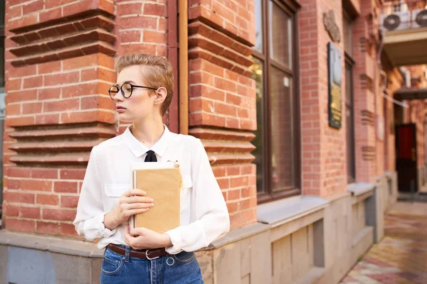 Hezká žena s brýlemi procházky po městě s knihou vzdělávání — Stock fotografie