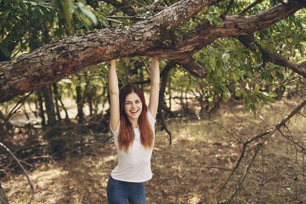 Vacker kvinna nära ett träd utomhus i skogen frisk luft och resa — Stockfoto