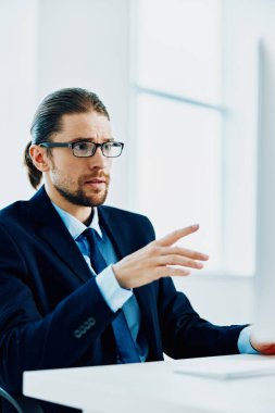 Masasında yazan gözlüklü takım elbiseli bir adam.