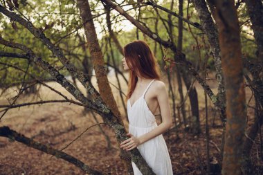 Yaz tatili için ağaçların yanında beyaz elbiseli bir kadın.