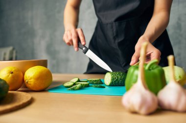 Mutfakta aşçı, izole edilmiş sebzeleri kesiyor.
