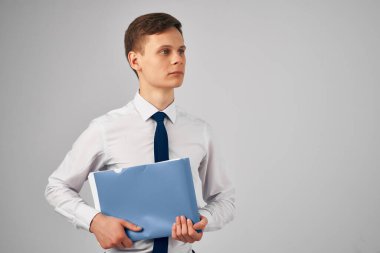 Ellerinde mavi klasör olan gömlekli adam gri arka plan