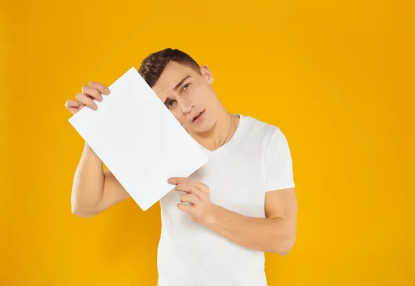 Homme avec feuille de papier publicité copie espace présentation jaune fond — Photo