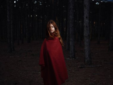 Ormanda yürüyen kırmızı ekose elbiseli kadın. 