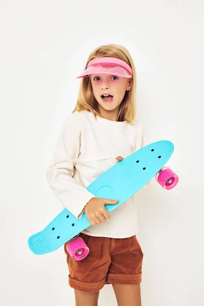 Porträtt av ung leende unge rosa mössa med skateboard ljus bakgrund — Stockfoto