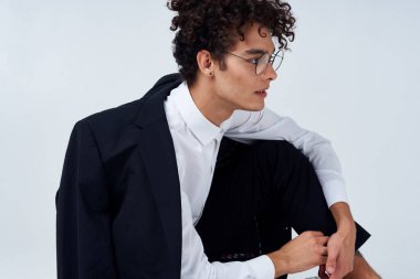 Siyah ceketli adam zarif bir şekilde yerde oturuyor.