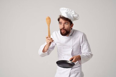Aşçı üniformalı bir adam, ellerinde tavayla yemek pişiriyor.