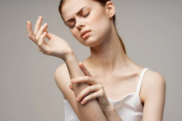 Γυναίκα σε λευκό t-shirt κρατώντας το χέρι προβλήματα υγείας κοινό στούντιο θεραπεία — Φωτογραφία Αρχείου