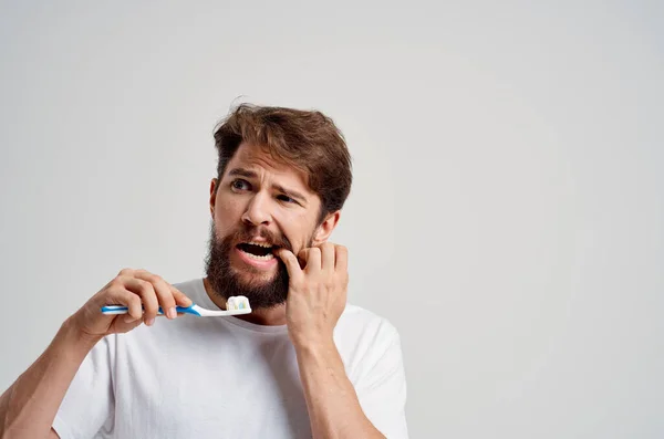 Vousatý muž hygiena zubní pasta ráno světlo pozadí — Stock fotografie