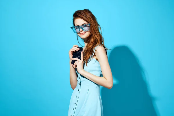 Retrato de uma mulher em um vestido azul com telefone na mão fundo azul — Fotografia de Stock