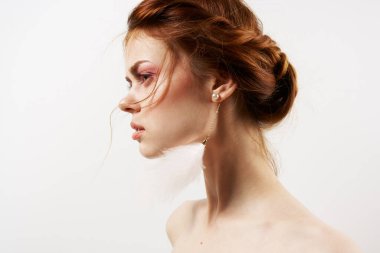 Çıplak omuzlu, parlak makyaj küpeli bir kadın.