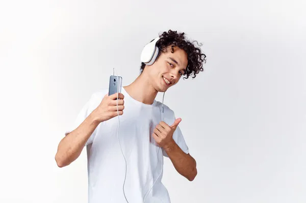 Curly-haired guy in white t-shirt with headphones music technology entertainment — Stock Photo, Image