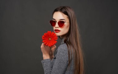 Stüdyoda elinde çiçek tutan güneş gözlüğü takan güzel bir esmer. Yüksek kalite fotoğraf