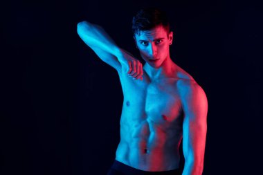 Kasları şişmiş erkek sporcu ve siyah arka planda gövdesi var.