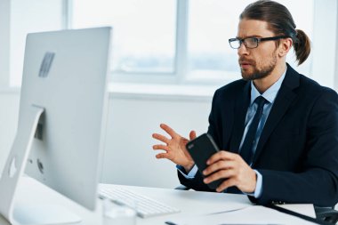 Takım elbiseli bir adam bilgisayarın önünde çalışıyor.