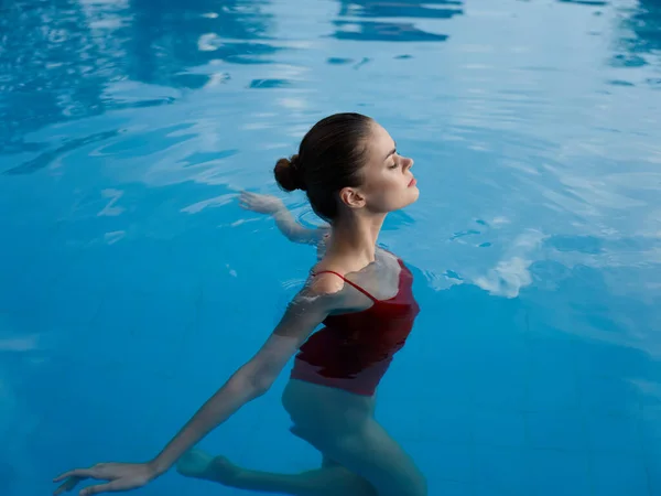 Женщина в отпуске Плавание в бассейне прозрачная вода красный купальник модель расслабиться — стоковое фото