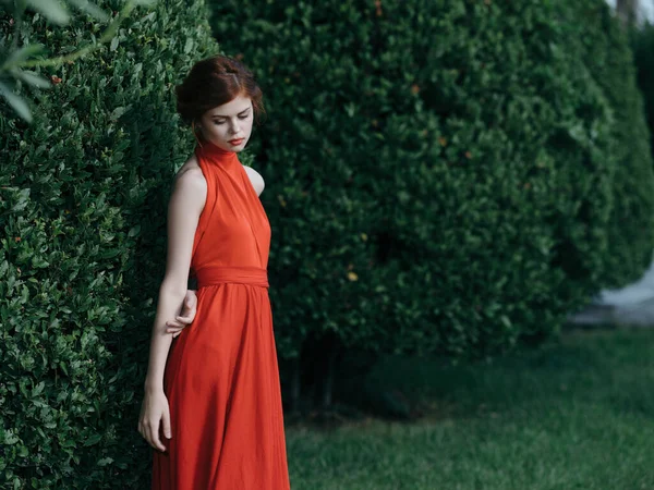 Nő piros ruhában séta a kertben gótikus természet — Stock Fotó