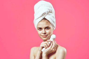 Kafasına havlu takmış bir kadın ellerinde masözler cilt bakımını temizliyor.