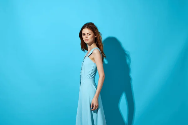 파란 드레스를 입고 푸른 배경 생활 방식을 하는 예쁜 여자 — 스톡 사진
