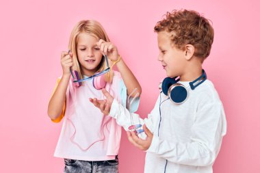 Pembe arka plan pozu veren kulaklık takan son moda erkek ve kız.