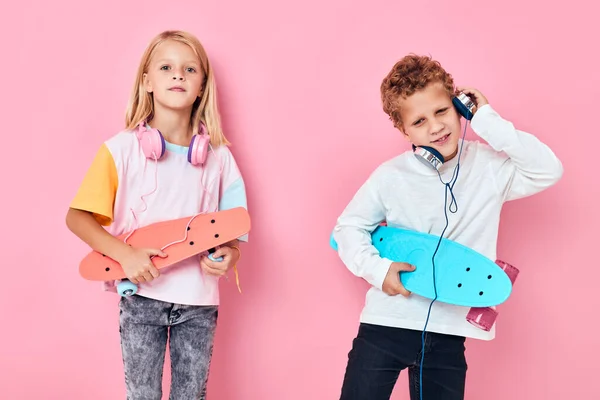 Lindo chico y chica sosteniendo monopatines entretenimiento auriculares música —  Fotos de Stock