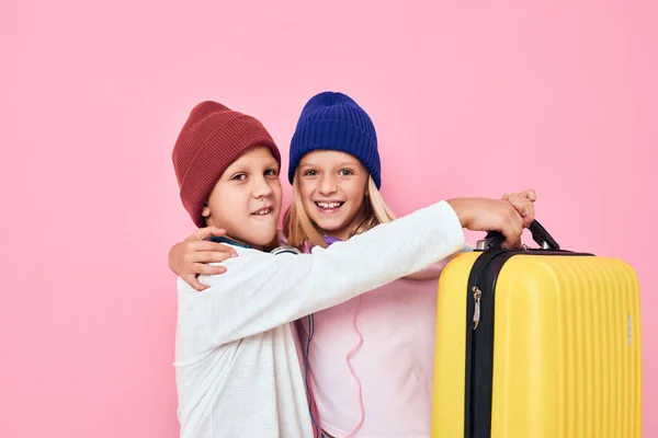 Портрет девочки и мальчика с желтым чемоданом в руках изолированный фон — стоковое фото