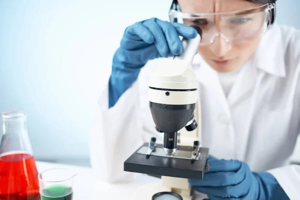 Kobieta w białym płaszczu patrząc przez eksperyment technologii mikroskopu — Zdjęcie stockowe