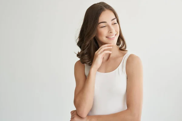Mulher alegre em uma camiseta branca cuidado do cabelo luz fundo — Fotografia de Stock