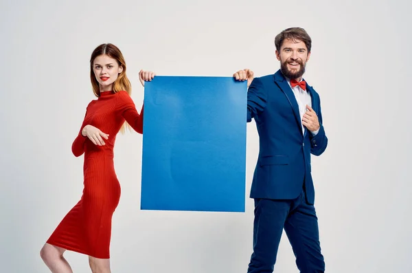 Un homme en costume à côté d'une femme en robe rouge affiche bleue publicité Espace Copier — Photo