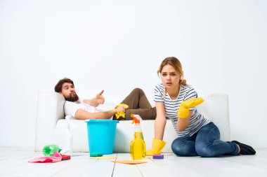 Kanepenin yanında genç bir çift koruyucu eldivenleri temizliyor.