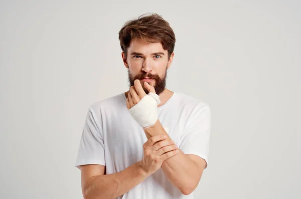 Paziente di sesso maschile in una t-shirt bianca con una mano fasciata in posa medicina ospedaliera — Foto Stock