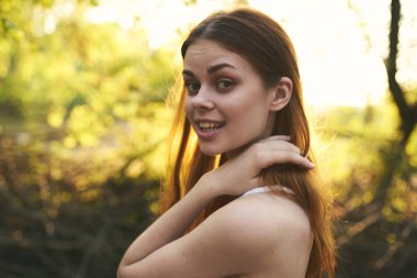 Beyaz elbiseli kadın saçını düzleştiriyor yeşil yapraklar doğayı terk ediyor.