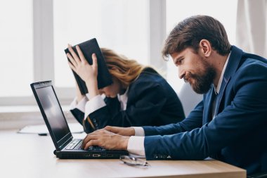 Meslektaşlar dizüstü bilgisayarın önünde profesyonellerin önünde oturuyorlar.