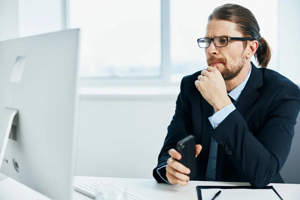 The man in a suit in the office gestures with his hands computer