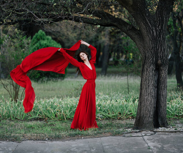 Woman in red dress in forest charm luxury tree. High quality photo