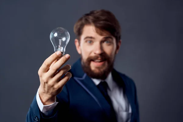 Hombre de negocios en un traje que sostiene una estrategia de idea de tecnología de lámpara —  Fotos de Stock