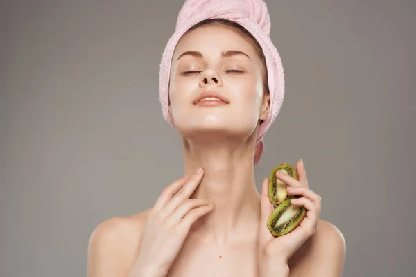 Vrouw met een handdoek op haar hoofd na douche kiwi in de hand bijgesneden uitzicht — Stockfoto