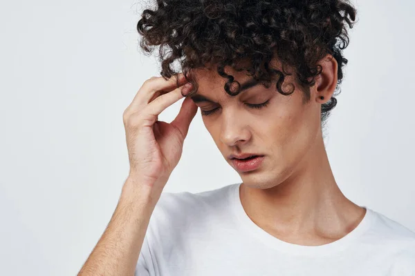 Gars aux cheveux bouclés dans un t-shirt blanc migraine mécontentement — Photo
