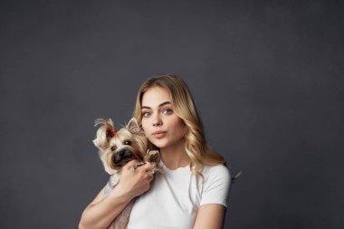 Küçük köpek makyajlı güzel bir kadın koyu bir arka plan oluşturuyor.