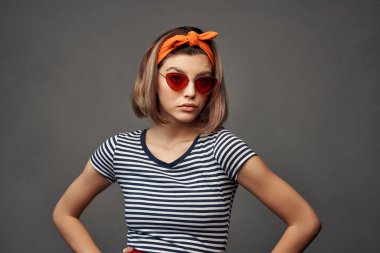 Kafasında turuncu bandaj olan güneş gözlüğü takan bir kadın.