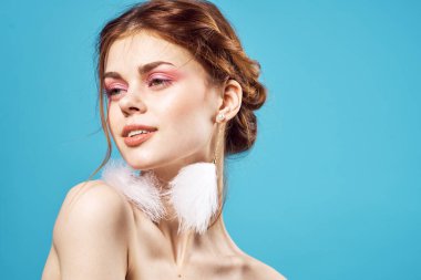 Neşeli kadın çıplak omuzlar ve tüylü küpeler parlak makyaj pozu.