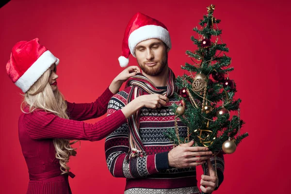 若いカップルクリスマスの装飾休日ポーズ赤の背景 — ストック写真