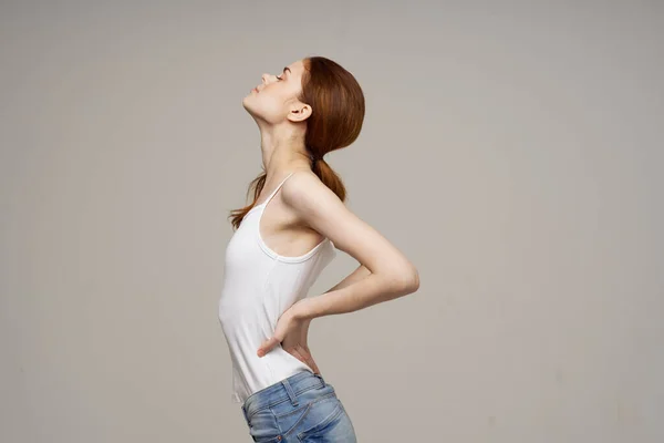 Γυναίκα σε λευκό t-shirt οσφυαλγία προβλήματα υγείας οστεοπόρωση στούντιο θεραπεία — Φωτογραφία Αρχείου