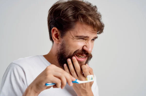 Emocionální muž hygiena zubní pasta ráno světlo pozadí — Stock fotografie