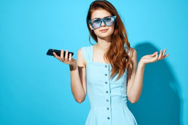 Kadın elbise ve gözlüklü, elinde telefon teknolojisiyle.