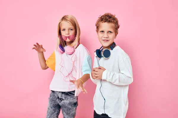 Portrét dívky a chlapce na sluchátkách pózování růžové barvy pozadí — Stock fotografie