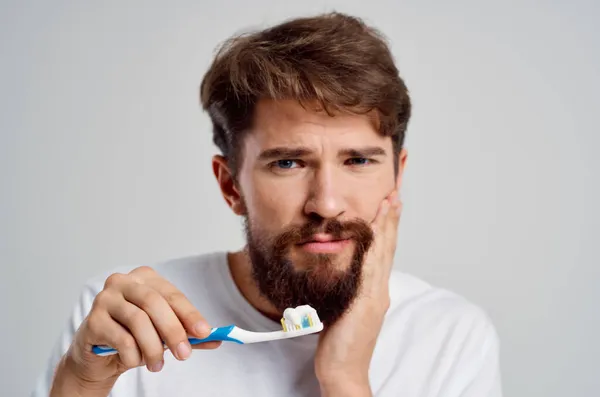 Barbudo hombre cuidado dental odontología dolor de muelas fondo claro — Foto de Stock