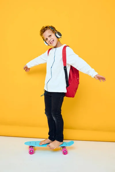 Glad pojke med skateboard i hörlurar isolerad bakgrund — Stockfoto